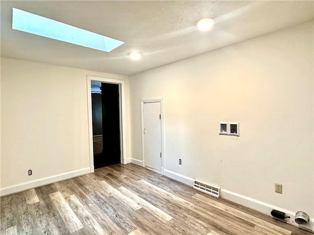 966 W Church St, Elmira, NY 14905 - empty room with a skylight, baseboards, and wood finished floors
