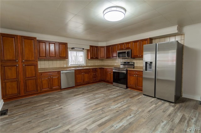 4 Division St, Van Buren, NY 13027 - kitchen featuring appliances with stainless steel finishes, light wood-style floors, decorative backsplash, brown cabinetry, and crown molding
