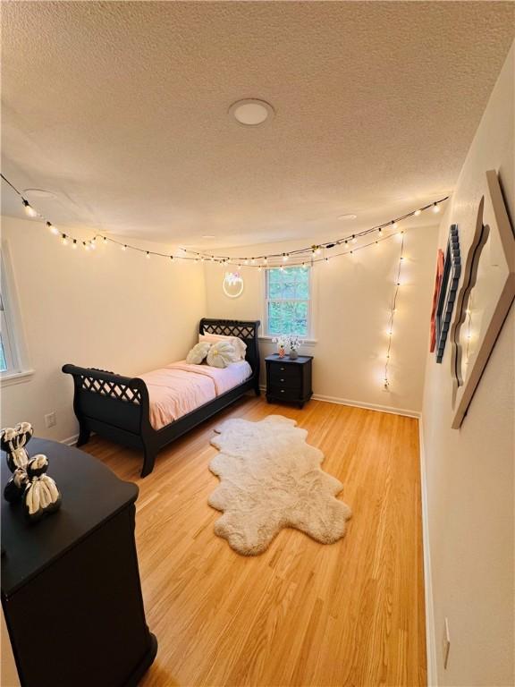 11 Laureldale Dr, Pittsford, NY 14534 - bedroom featuring a textured ceiling, wood finished floors, and baseboards