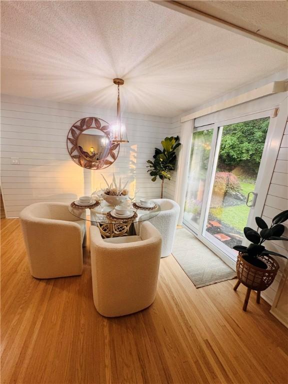 11 Laureldale Dr, Pittsford, NY 14534 - sitting room featuring wood finished floors, a textured ceiling, a chandelier, and wood walls