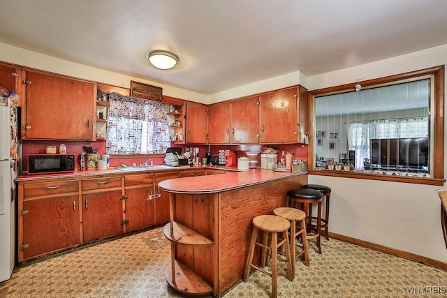 102 Wellworth Pl, Cheektowaga, NY 14225 - kitchen with open shelves, black microwave, light flooring, brown cabinetry, and a breakfast bar area