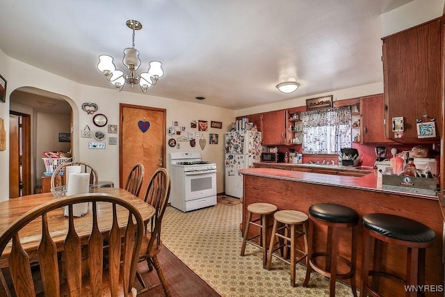 102 Wellworth Pl, Cheektowaga, NY 14225 - kitchen featuring white appliances, arched walkways, a peninsula, a chandelier, and light floors