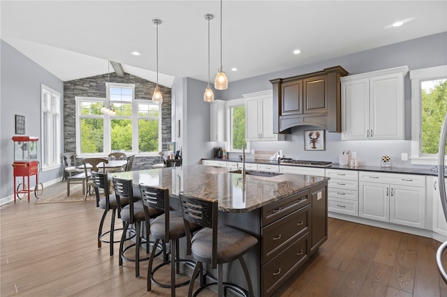 1915 Factors Walk, West Bloomfield, NY 14475 - kitchen featuring a sink, lofted ceiling, a center island with sink, white cabinetry, and dark stone counters
