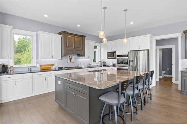 1915 Factors Walk, West Bloomfield, NY 14475 - kitchen with appliances with stainless steel finishes, a sink, an island with sink, light wood-style flooring, and dark stone counters
