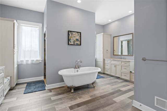 1915 Factors Walk, West Bloomfield, NY 14475 - full bath with vanity, wood finished floors, a soaking tub, baseboards, and recessed lighting