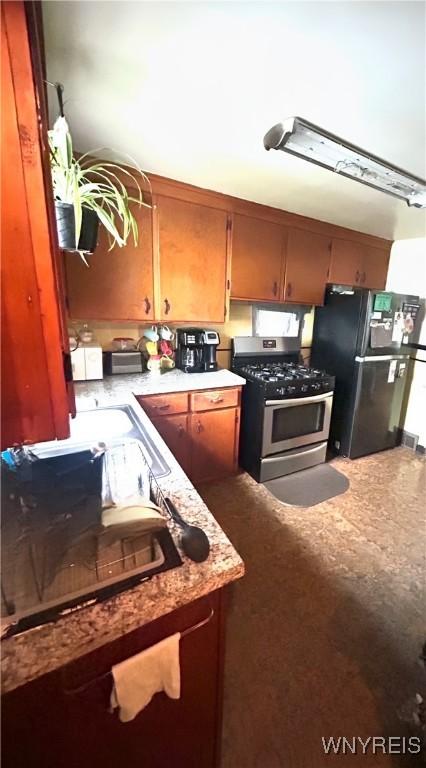 340 Martha Ave, Buffalo, NY 14215 - kitchen featuring stainless steel gas stove, freestanding refrigerator, light countertops, and brown cabinetry