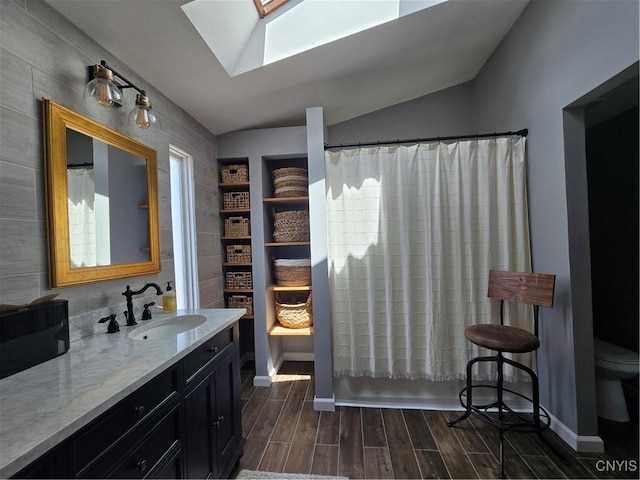 4982 Alfred Dr, Clay, NY 13090 - bathroom featuring a skylight, vanity, toilet, wood finished floors, and lofted ceiling