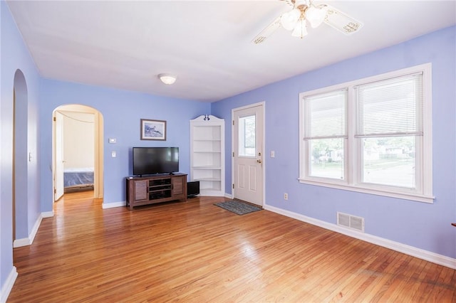 223 S Ave, Parma, NY 14468 - unfurnished living room featuring arched walkways, light wood-style flooring, a ceiling fan, and baseboards