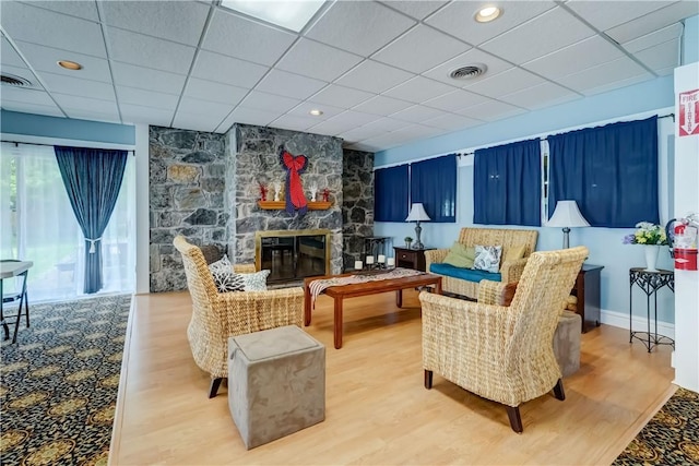 503 Valley Creek Rd, Gates, NY 14624 - living area featuring wood finished floors, a stone fireplace, a paneled ceiling, and baseboards