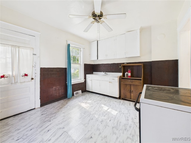 465 10th St, Niagara Falls, NY 14303 - kitchen featuring white range with electric cooktop, white cabinets, a ceiling fan, a sink, and a wainscoted wall