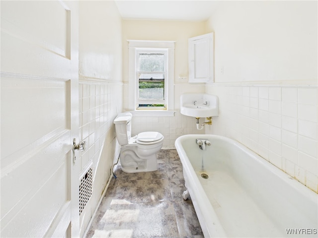465 10th St, Niagara Falls, NY 14303 - bathroom with a bathtub, toilet, a sink, a wainscoted wall, and tile walls