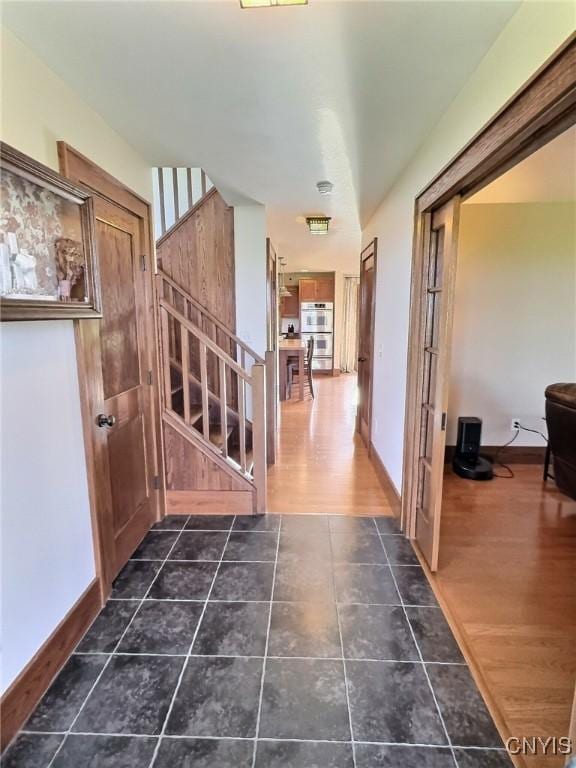 7294 Chase Rd, Pompey, NY 13063 - hallway with stairs, dark tile patterned floors, and baseboards