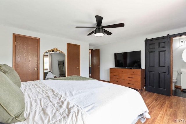 4292 Persimmon, Clay, NY 13090 - bedroom with light wood finished floors, two closets, a barn door, ceiling fan, and connected bathroom