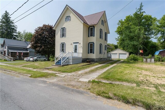 25 Waid St, Gouverneur, NY 13642 - view of front of property with a garage, an outbuilding, a front yard, and metal roof