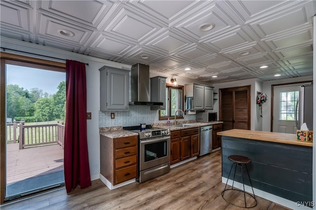 25 Waid St, Gouverneur, NY 13642 - kitchen with stainless steel appliances, wall chimney range hood, a sink, an ornate ceiling, and light wood-style flooring