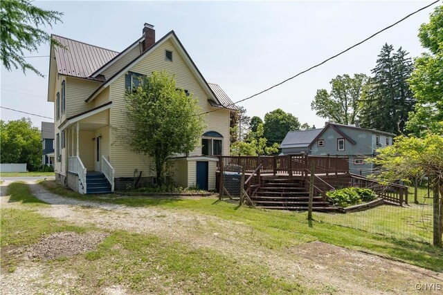 25 Waid St, Gouverneur, NY 13642 - view of property exterior featuring a chimney, metal roof, stairway, a yard, and a deck