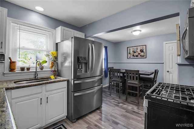126 Midland Dr, Cheektowaga, NY 14225 - kitchen featuring stainless steel appliances, a sink, white cabinetry, light wood-style flooring, and dark stone counters