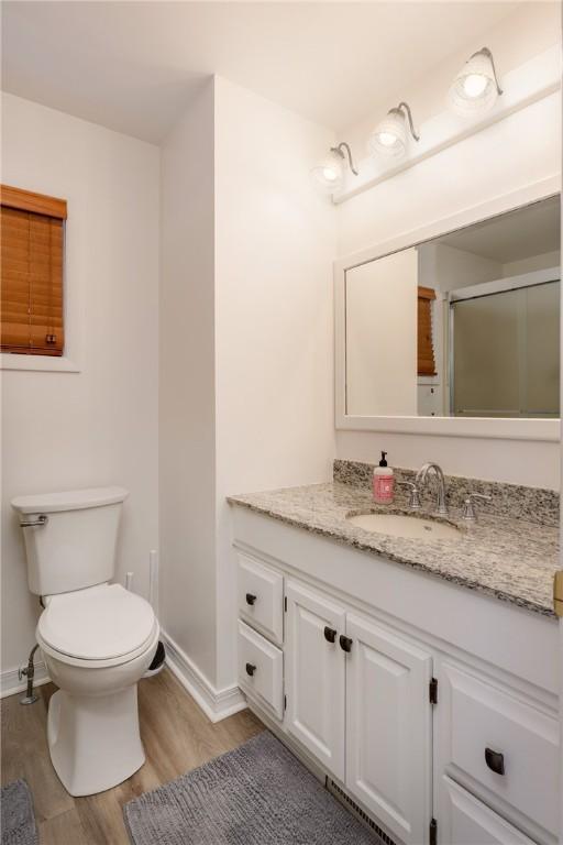 39 Sunnyside Dr, Elmira, NY 14905 - bathroom featuring wood finished floors, vanity, baseboards, toilet, and an enclosed shower