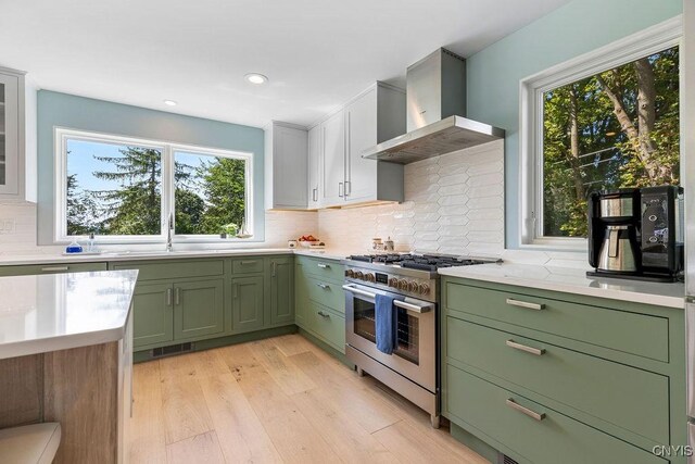 3 Elson Ln, Skaneateles, NY 13152 - kitchen with green cabinetry, stainless steel range with gas stovetop, wall chimney range hood, light countertops, and a sink