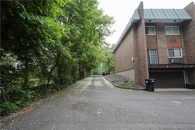 1215-29 James St, Syracuse, NY 13203 - view of property exterior featuring a standing seam roof, brick siding, a garage, metal roof, and driveway
