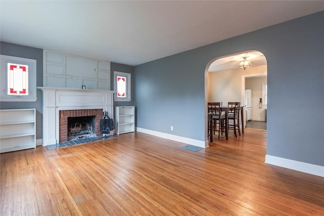 3215 E River Rd, Henrietta, NY 14623 - living room with light wood finished floors, arched walkways, a fireplace, and baseboards