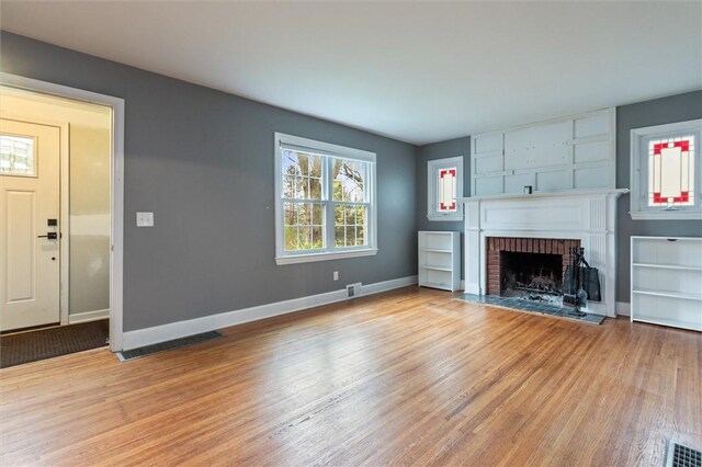3215 E River Rd, Henrietta, NY 14623 - unfurnished living room featuring light wood finished floors, baseboards, and a brick fireplace