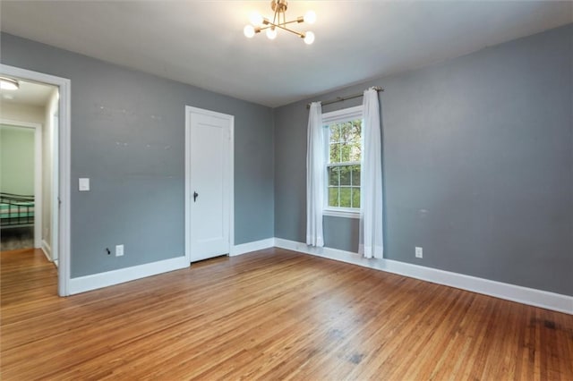 3215 E River Rd, Henrietta, NY 14623 - unfurnished bedroom featuring a chandelier, baseboards, and light wood-style floors