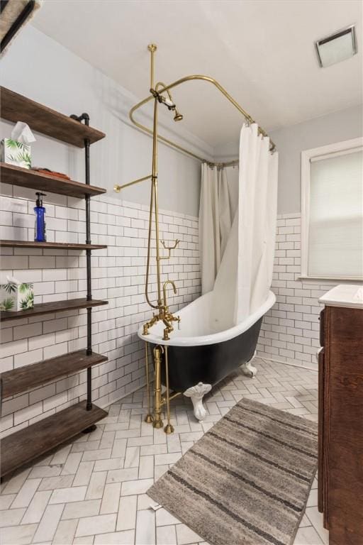 3215 E River Rd, Henrietta, NY 14623 - bathroom with tile walls, a freestanding tub, vanity, wainscoting, and a shower with shower curtain