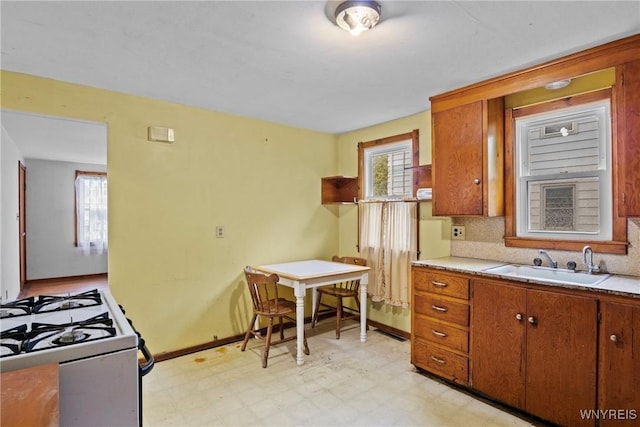99 Kamper Ave, Buffalo, NY 14210 - kitchen featuring a sink, gas range gas stove, light countertops, brown cabinetry, and plenty of natural light