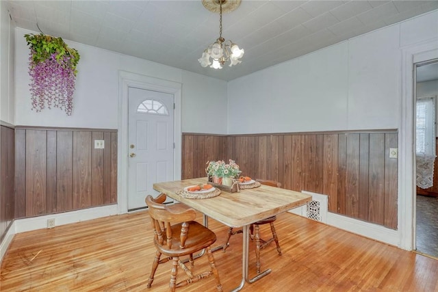 135 Cameron St, Rochester, NY 14606 - dining area featuring wooden walls, light wood-style floors, a wainscoted wall, and a chandelier