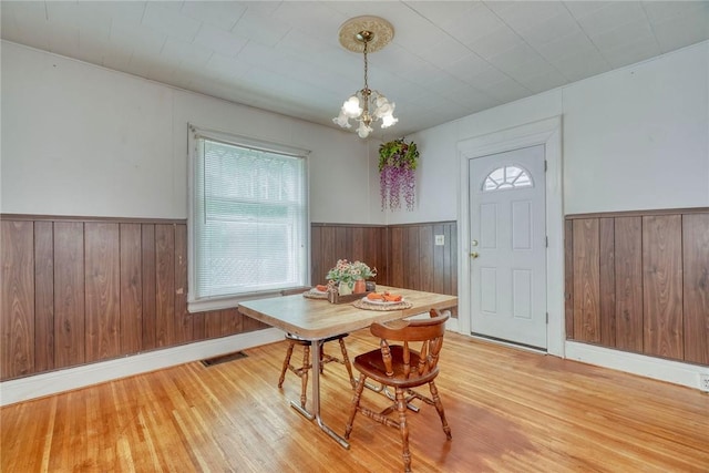 135 Cameron St, Rochester, NY 14606 - dining space with a wainscoted wall, wooden walls, a chandelier, and light wood-type flooring