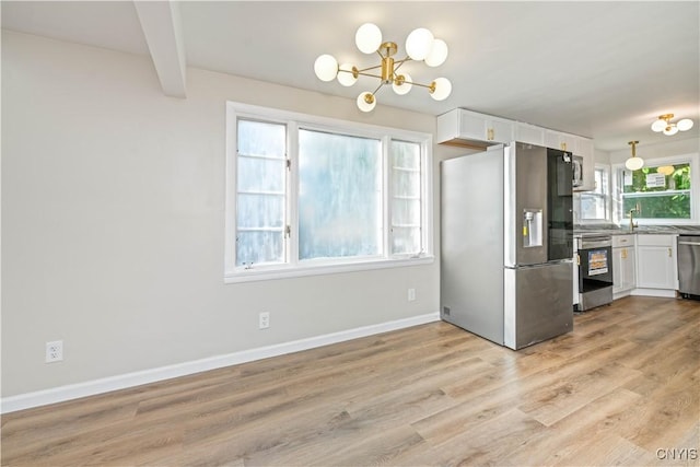 124 Aurora St, Rochester, NY 14621 - kitchen featuring stainless steel appliances, white cabinetry, a chandelier, light wood finished floors, and baseboards