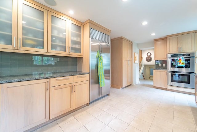 313 Pelham Rd, Brighton, NY 14610 - kitchen with appliances with stainless steel finishes, light brown cabinets, dark stone counters, backsplash, and glass insert cabinets