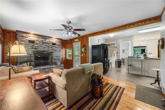 15205 W Lake Rd, Pulteney, NY 14418 - living room with wood walls, ceiling fan, a fireplace, light wood finished floors, and ornamental molding