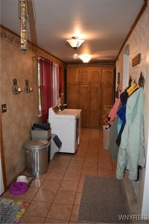 4571 Budd Rd, Cambria, NY 14094 - laundry area featuring independent washer and dryer, light tile patterned flooring, and cabinet space