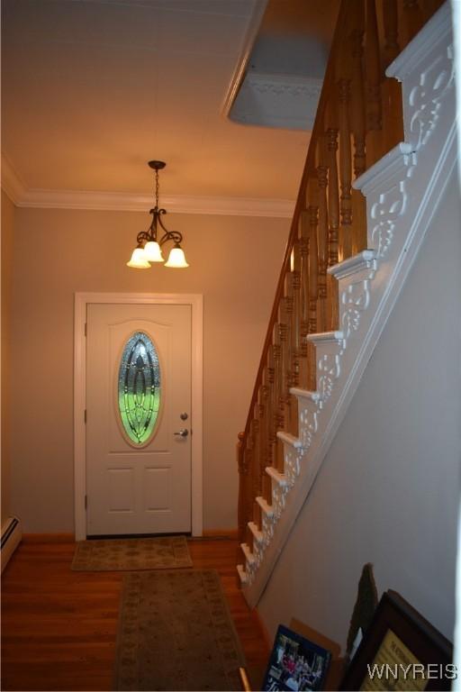 4571 Budd Rd, Cambria, NY 14094 - foyer entrance featuring stairway, wood finished floors, a chandelier, ornamental molding, and baseboards