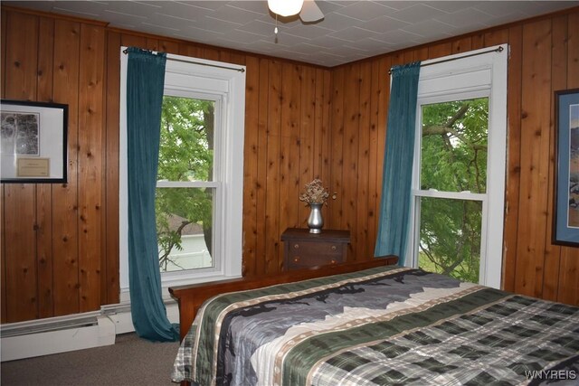 4571 Budd Rd, Cambria, NY 14094 - carpeted bedroom featuring wood walls, a baseboard heating unit, and a ceiling fan