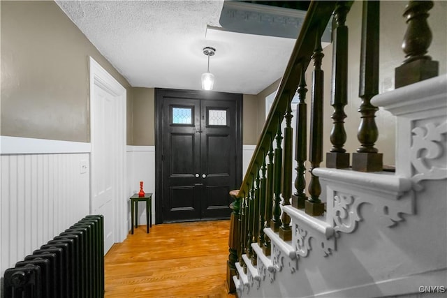 4937 W Seneca, Onondaga, NY 13215 - entryway with radiator heating unit, stairs, a wainscoted wall, light wood finished floors, and a textured ceiling