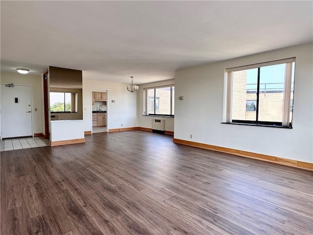 2501 E Ave, Brighton, NY 14610 - unfurnished living room with radiator heating unit, dark wood finished floors, and plenty of natural light