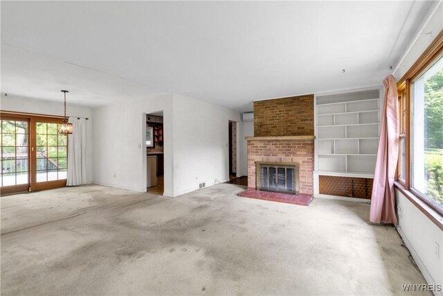 1701 Billington Rd, Elma, NY 14052 - unfurnished living room featuring a fireplace, a chandelier, built in shelves, light colored carpet, and baseboards