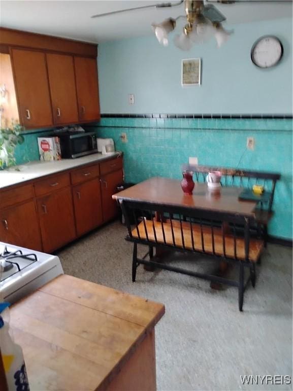 72 Nicholson St, Buffalo, NY 14214 - kitchen with brown cabinets, a wainscoted wall, a ceiling fan, and light countertops
