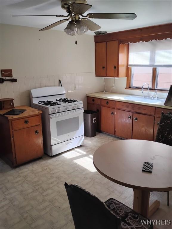 72 Nicholson St, Buffalo, NY 14214 - kitchen with white range with gas stovetop, tile walls, light floors, a ceiling fan, and light countertops