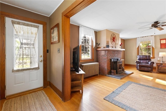 707 Hubbell Rd, Ogden, NY 14428 - entrance foyer with radiator, a ceiling fan, a wood stove, wood finished floors, and baseboards