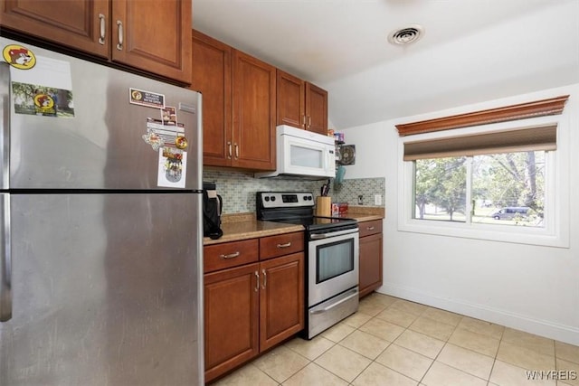 596 Longmeadow Rd, Amherst, NY 14226 - kitchen with stainless steel appliances, backsplash, light tile patterned flooring, baseboards, and brown cabinetry