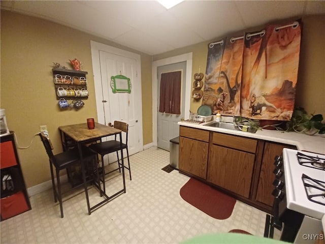 58-60 Lansing St, Auburn, NY 13021 - kitchen featuring gas stove, a sink, light countertops, light floors, and baseboards