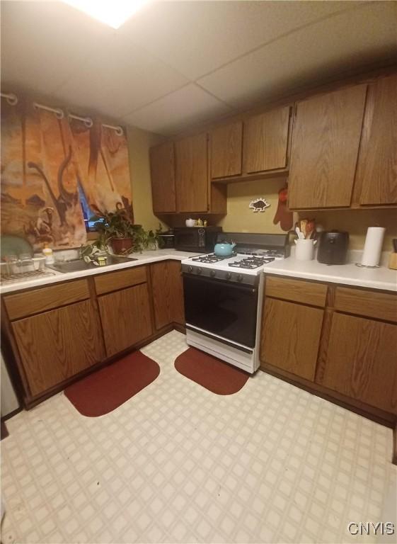 58-60 Lansing St, Auburn, NY 13021 - kitchen with white gas range oven, brown cabinets, light countertops, and light flooring