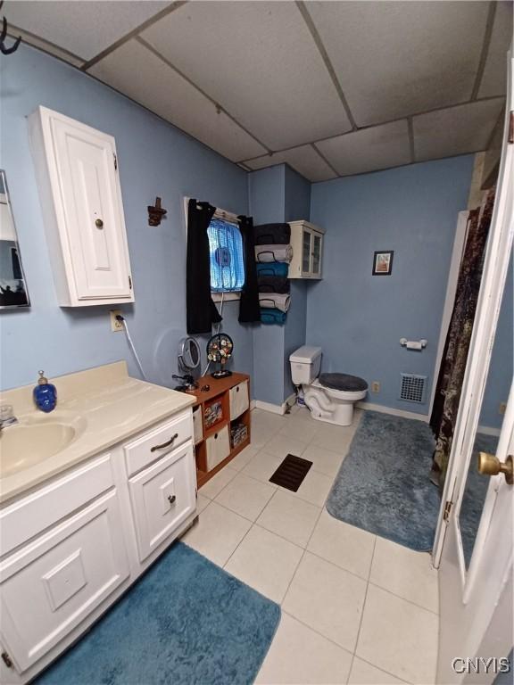58-60 Lansing St, Auburn, NY 13021 - full bathroom with a drop ceiling, vanity, tile patterned flooring, toilet, and baseboards