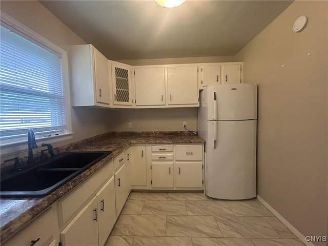 719 Dawes Ave, Utica, NY 13502 - kitchen with freestanding refrigerator, a sink, light marble finish floors, white cabinetry, and glass insert cabinets