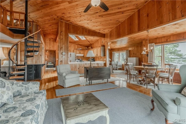 48785 Bamerick Rd, Alexandria, NY 13679 - living area with vaulted ceiling, stairway, wood walls, wood finished floors, and a ceiling fan