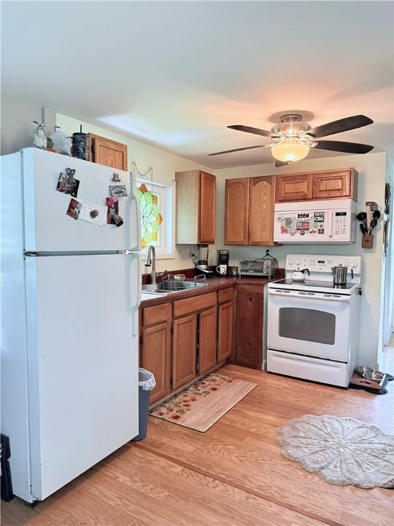 3679 County Highway 35, Middlefield, NY 13450 - kitchen featuring white appliances, a sink, light wood-style flooring, dark countertops, and brown cabinetry